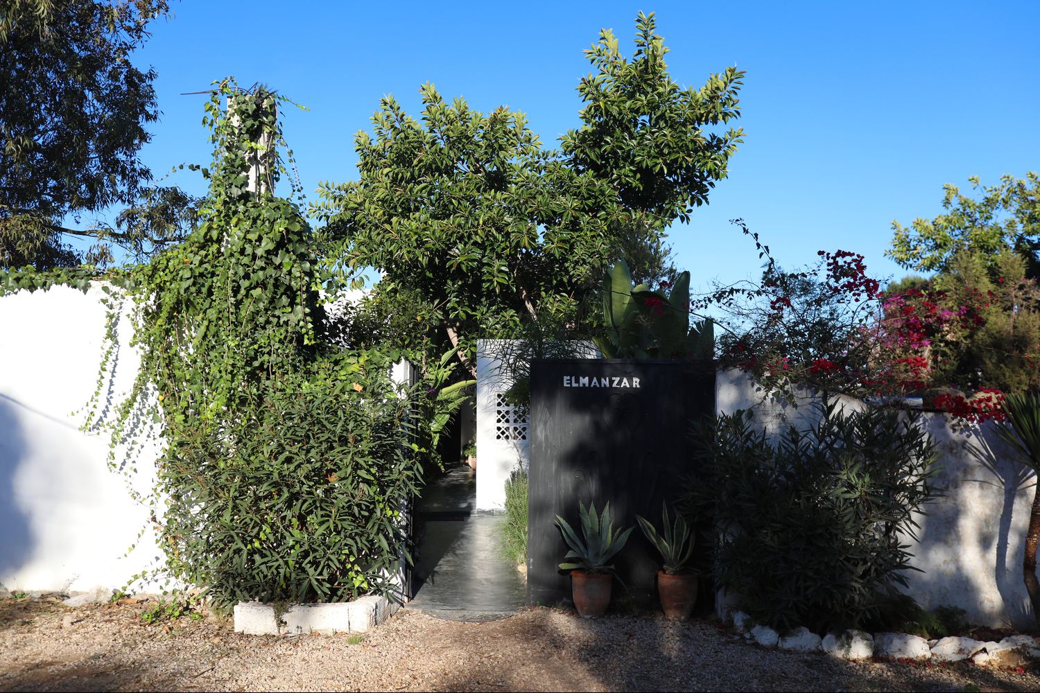 Le jardin fleuri d'El Manzar et son portail de fer, côté médina