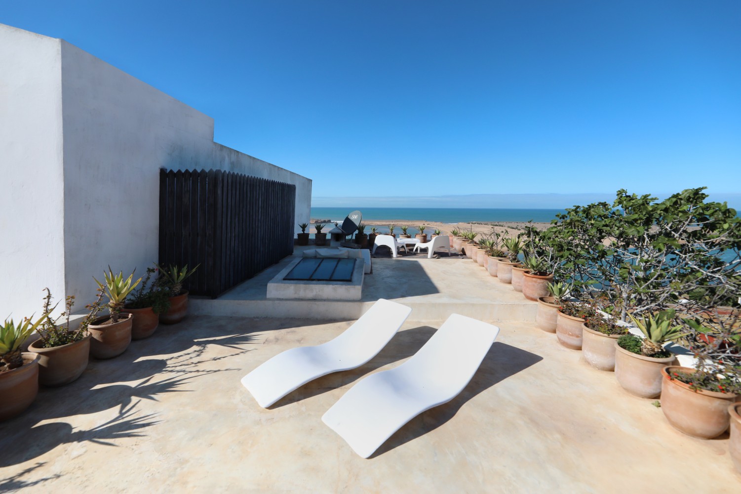 La terrasse haute d&rsquo;El Manzar &mdash; transats blancs et potées de terre cuite face à la lagune et à l&rsquo;océan
